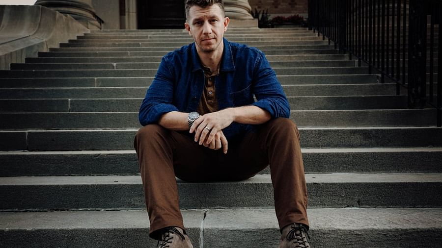 Man in stylish fall outfit with patterned shirt, cardigan, and leather boots